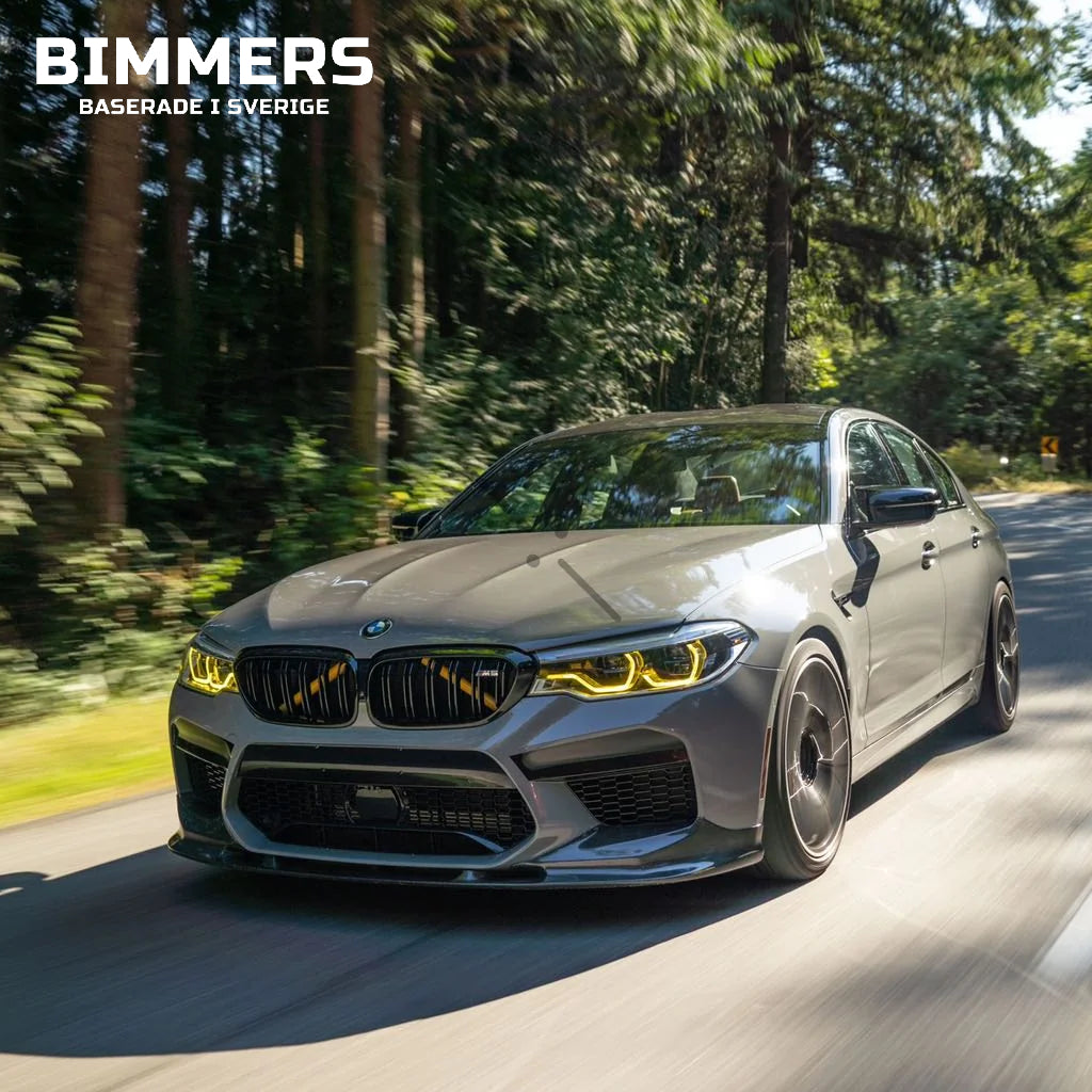 Grå BMW F90 med gula DRL som kör på gatan