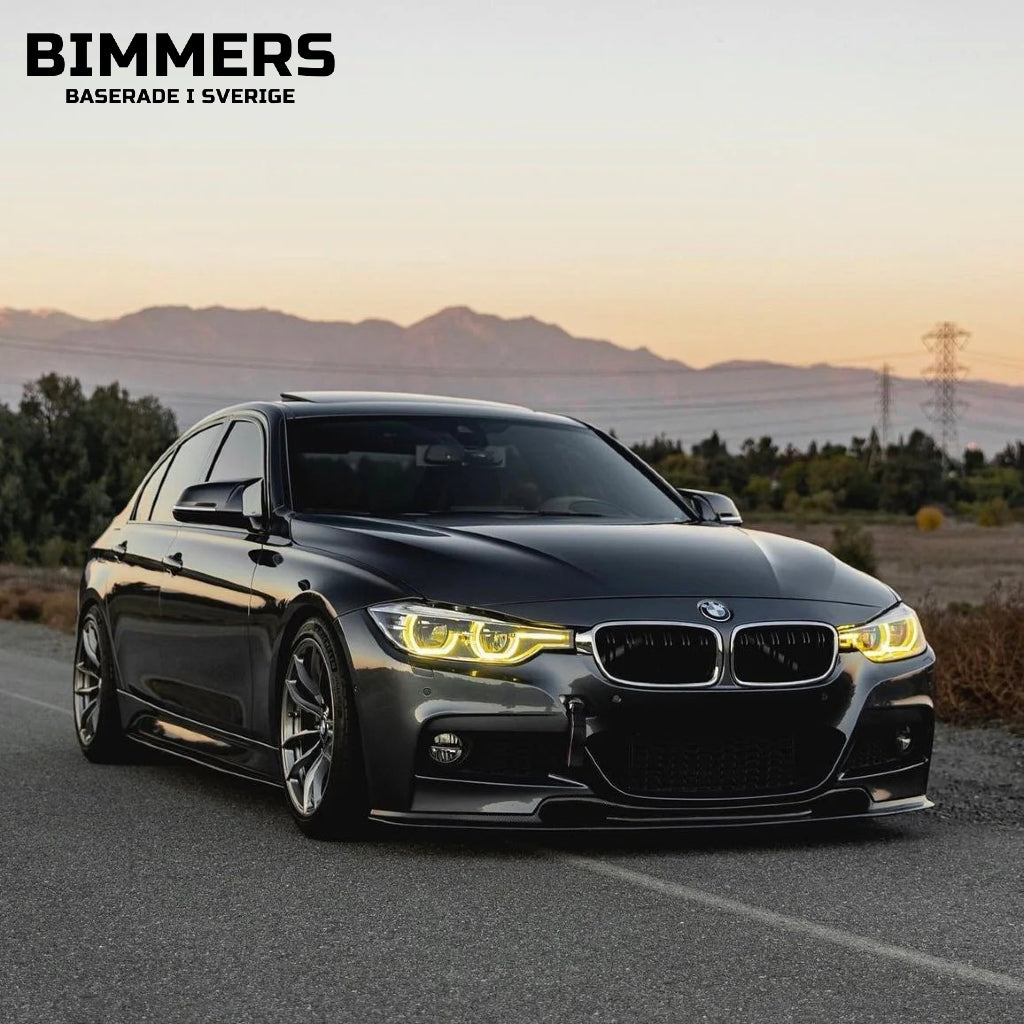 En mörkgrå BMW 3-serie F30 med gula DRl, parkerad vid sidan av gatan