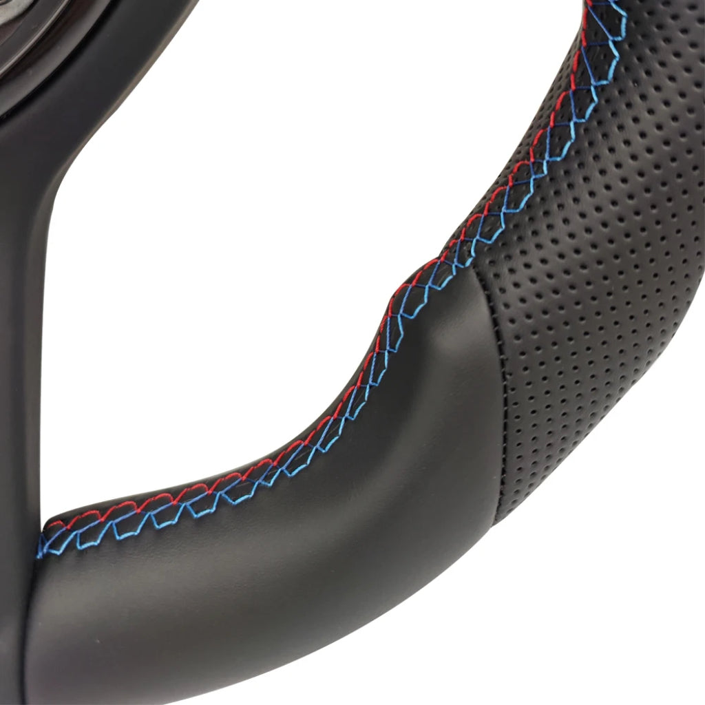 Närbild på läderklädsel med slätt och perforerat läder samt M-färgade sömmar. För BMW M-Sport flat bottom svart ratt F-serien.