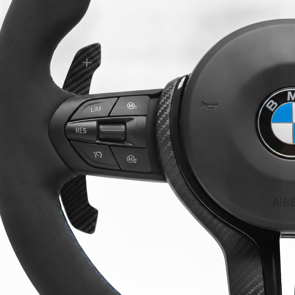 Närbild på multifunktionsknappar för farthållare, M1, M2 på Bimmers™ BMW M-Sport matt kolfiber svart ratt med magnetiska kolfiber paddlar F-serien.