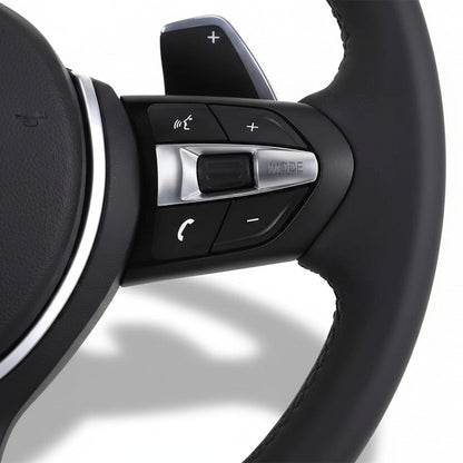 Närbild på multifunktionsknappar för volym och samtal på BMW M-Sport ratt.