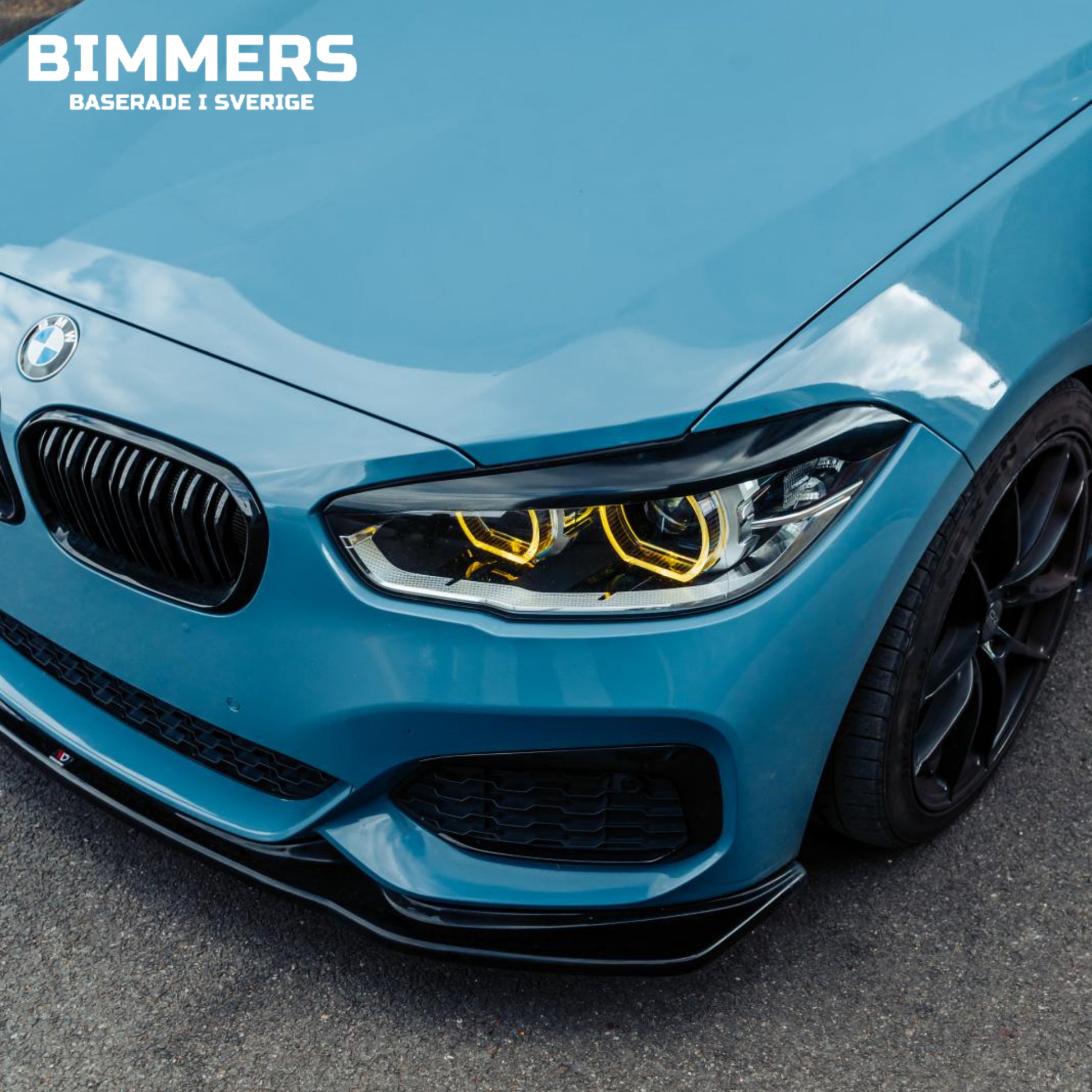 Närbild av en blå BMW F20 med gula DRL installerade