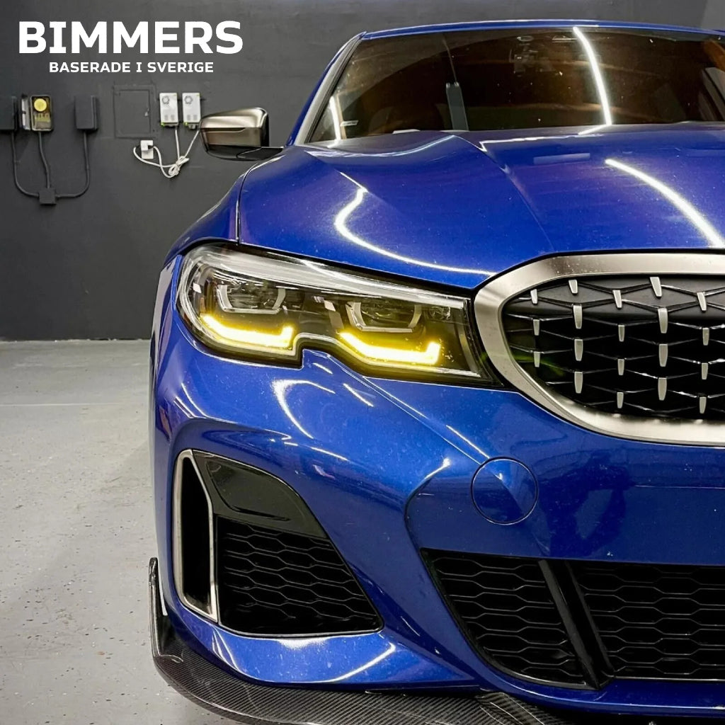 Närbild på en BMW G20 Standard LED-strålkastare med tända gula DRL-ljus på blå bil