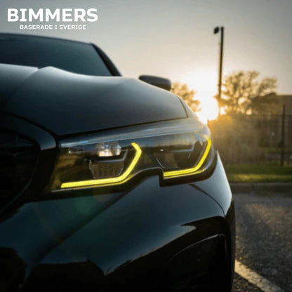 Närbild på en BMW G20 Standard LED-strålkastare med tända gula DRL-ljus  solljus